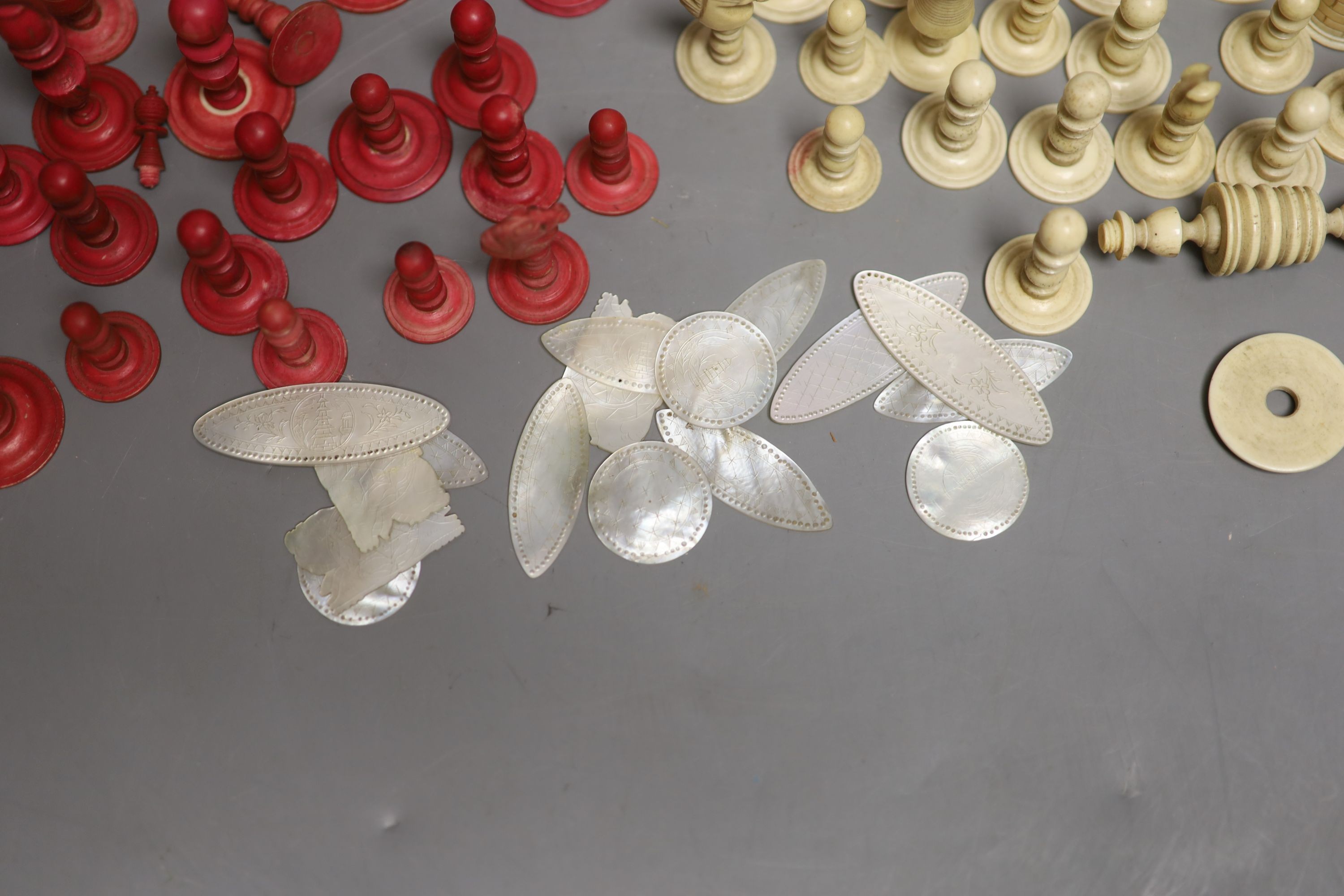 A set of 19th century red stained and natural bone chess pieces and a collection of etched mother of pearl bezique counters